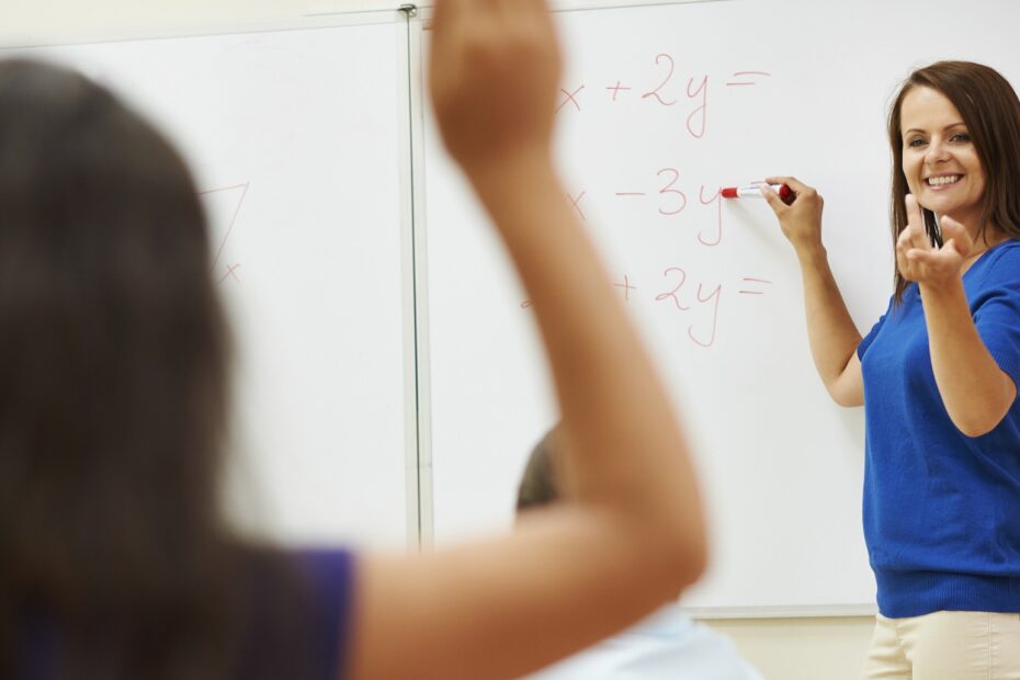 criança levantando a mão para responder calculo matemático escrito pela professora