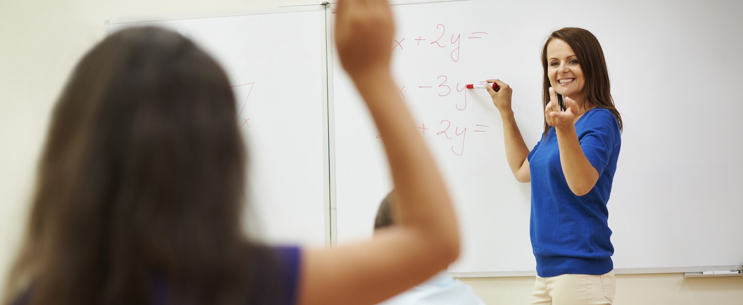criança levantando a mão para responder calculo matemático escrito pela professora