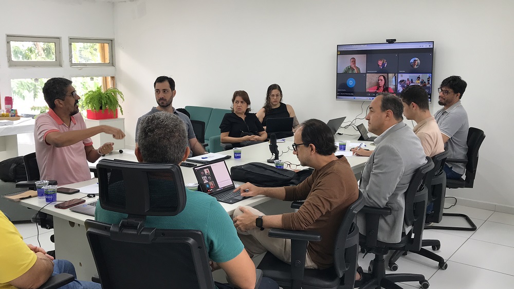 Representantes do NEES e do Odoo em reunião sentados ao redor de uma mesa retangular branca