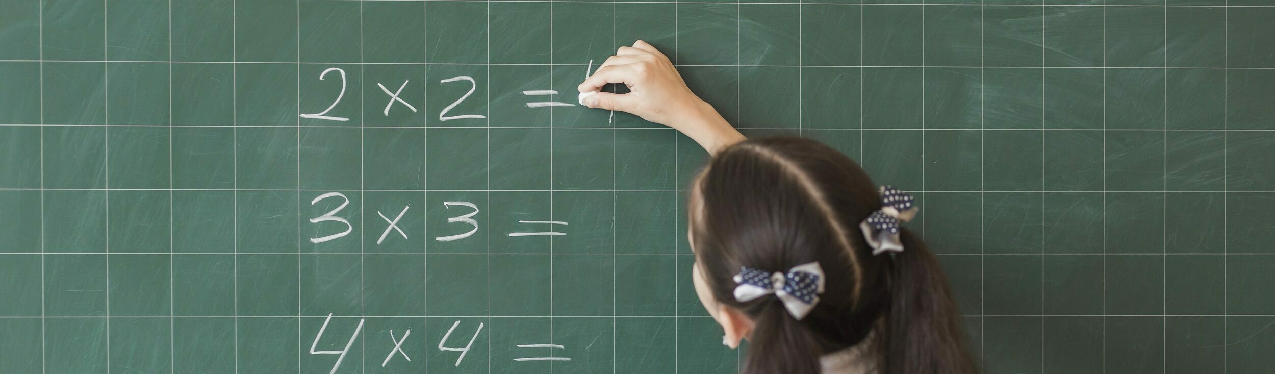 Imagem de Freepik mostra garota escrevendo cálculos matemáticos no quadro negro
